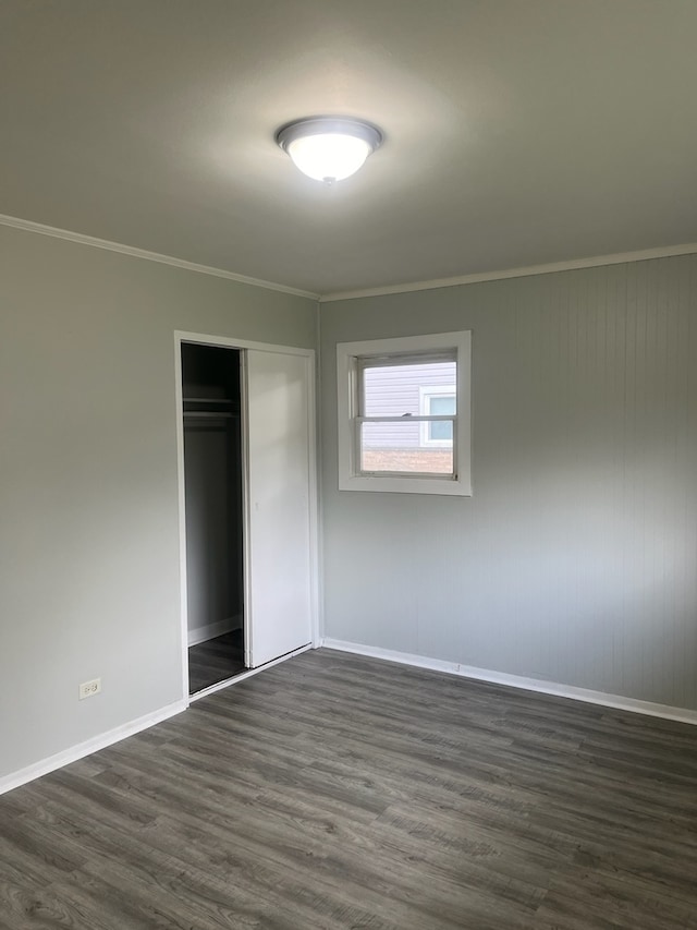 unfurnished bedroom featuring ornamental molding, dark wood-type flooring, and a closet