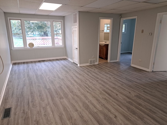 spare room with a drop ceiling and hardwood / wood-style flooring