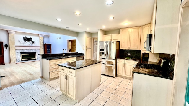 kitchen with a kitchen island, light hardwood / wood-style flooring, stainless steel appliances, dark stone countertops, and sink