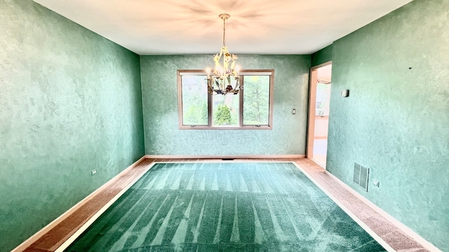 carpeted empty room featuring an inviting chandelier