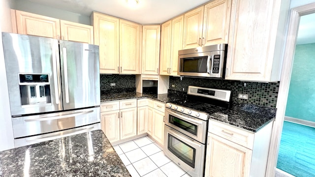 kitchen with light tile patterned floors, tasteful backsplash, appliances with stainless steel finishes, and dark stone counters