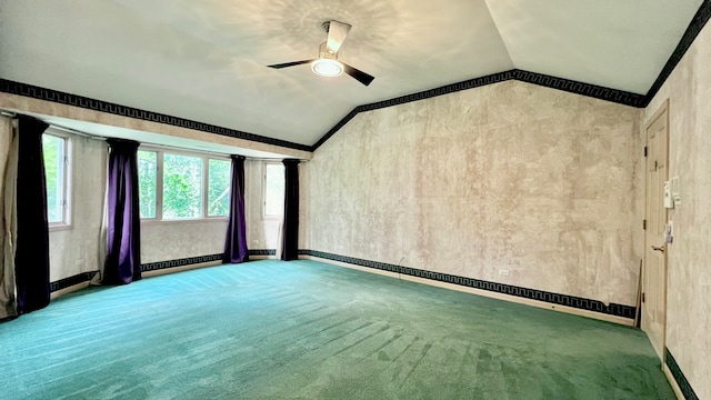 carpeted spare room featuring ornate columns, vaulted ceiling, and ceiling fan