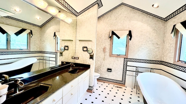 bathroom featuring toilet, ornamental molding, vanity, and a bath