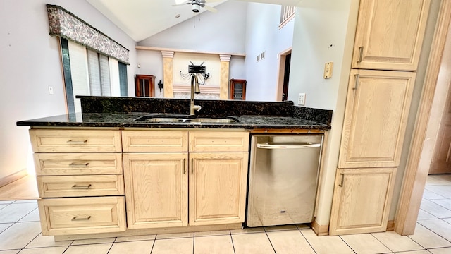 kitchen featuring stainless steel dishwasher, sink, vaulted ceiling, and dark stone countertops