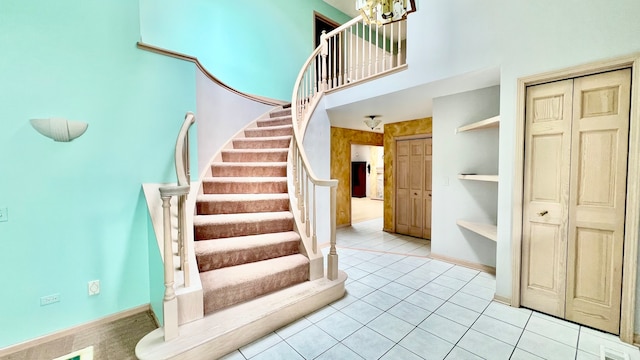 staircase with tile patterned floors and a high ceiling