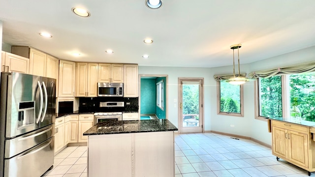 kitchen with appliances with stainless steel finishes, a kitchen island, pendant lighting, dark stone countertops, and light tile patterned floors