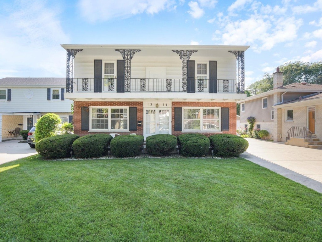 view of front of home with a balcony and a front lawn