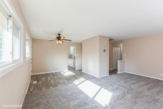 carpeted spare room featuring baseboards, ceiling fan, and wood finished floors