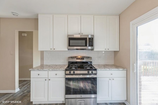 kitchen with white cabinets, light stone countertops, appliances with stainless steel finishes, baseboards, and tasteful backsplash