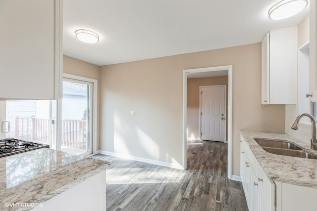 kitchen featuring sink, white cabinetry, light stone counters, and dark hardwood / wood-style floors