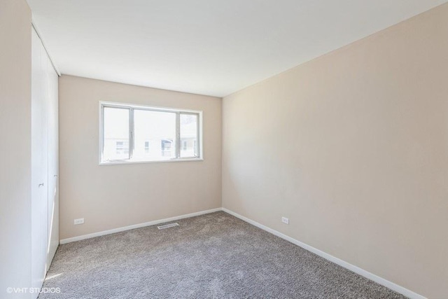 carpeted empty room featuring baseboards and visible vents