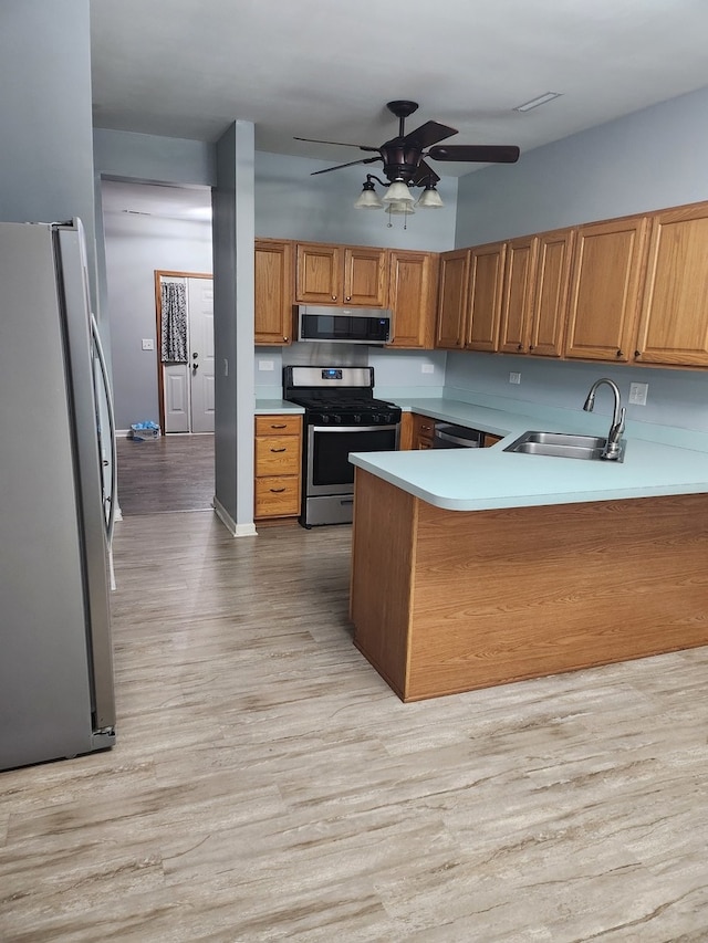 kitchen featuring sink, appliances with stainless steel finishes, kitchen peninsula, and light wood-type flooring