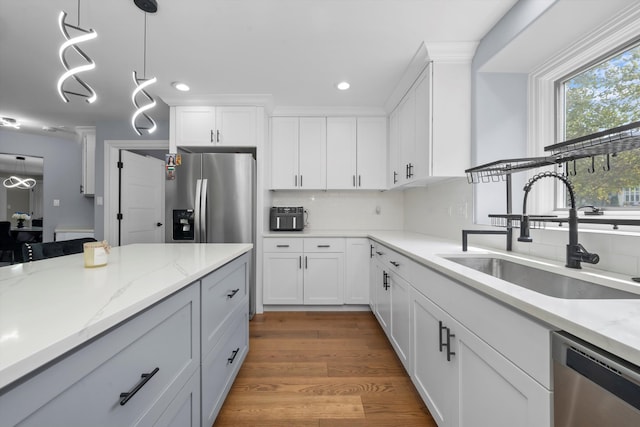 kitchen featuring decorative light fixtures, white cabinets, stainless steel appliances, and sink