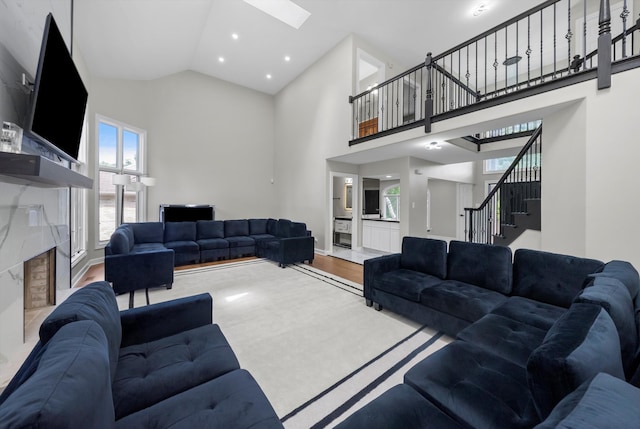 living room with hardwood / wood-style floors, high vaulted ceiling, and a skylight