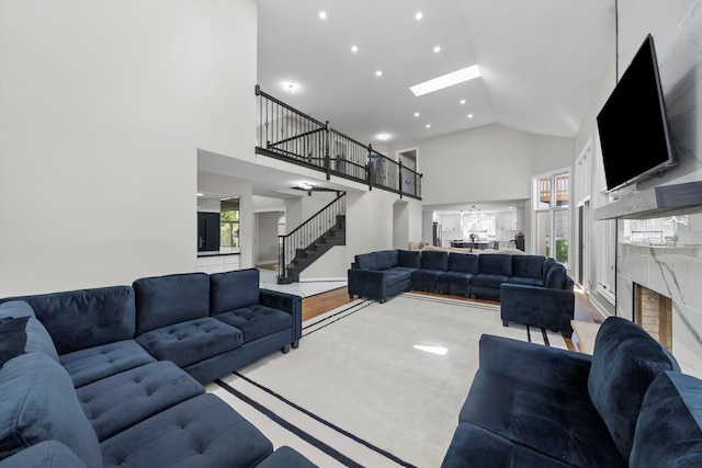 living room with light hardwood / wood-style flooring, high vaulted ceiling, a skylight, and a wealth of natural light