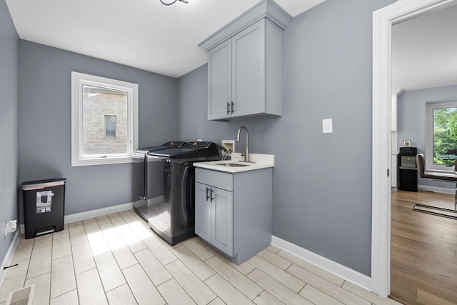 laundry room featuring sink, washer and dryer, cabinets, and light hardwood / wood-style floors