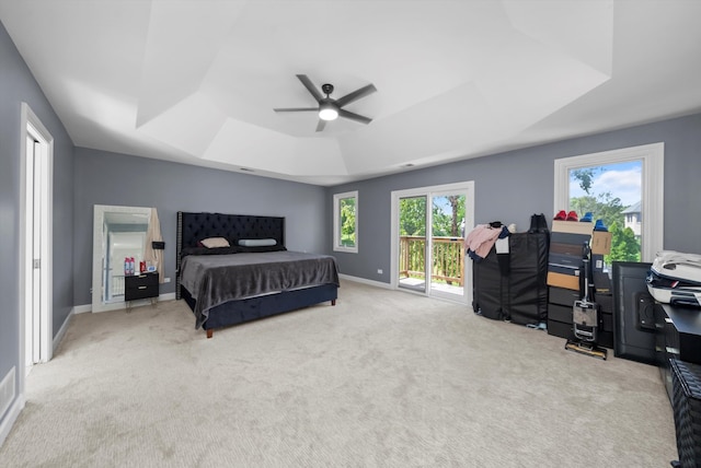 bedroom with a raised ceiling, light colored carpet, access to outside, and ceiling fan