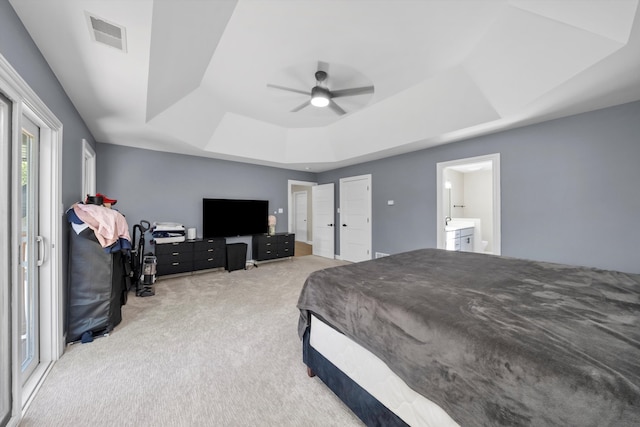 bedroom with ensuite bathroom, a tray ceiling, carpet, and ceiling fan