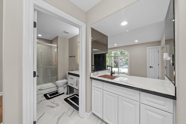 bathroom featuring vanity, a shower with shower door, and toilet