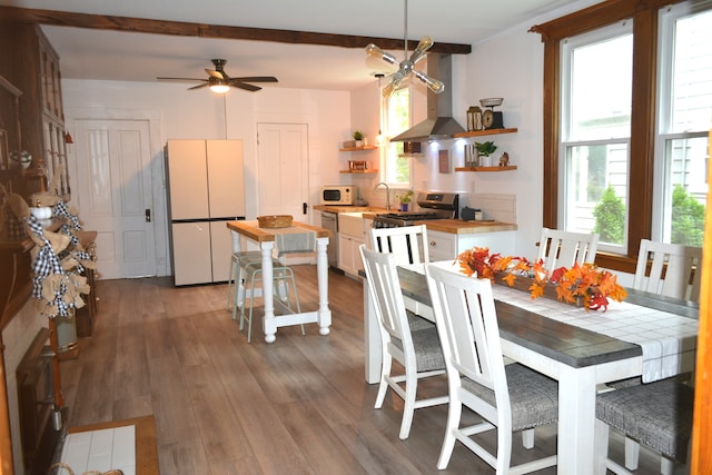 dining area with beamed ceiling, hardwood / wood-style floors, and ceiling fan