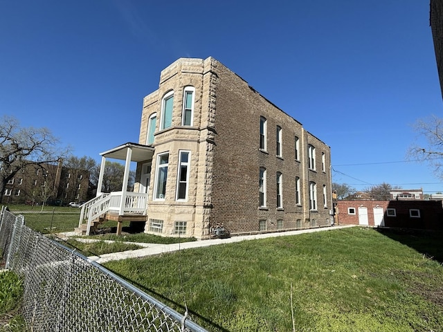 view of home's exterior featuring stone siding, fence, and a lawn