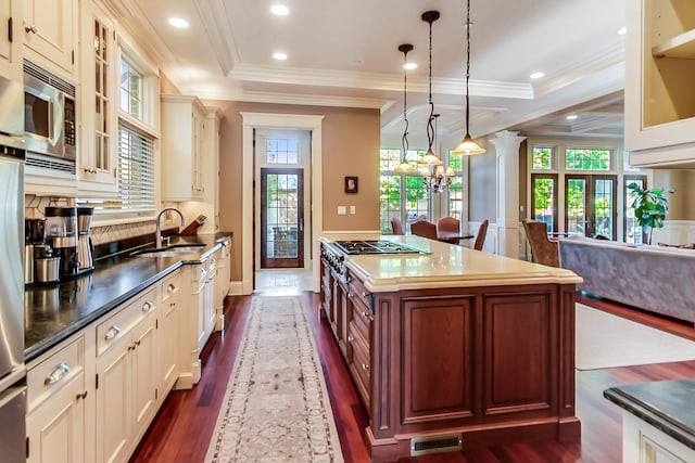 kitchen with appliances with stainless steel finishes, sink, a kitchen island, pendant lighting, and dark hardwood / wood-style floors