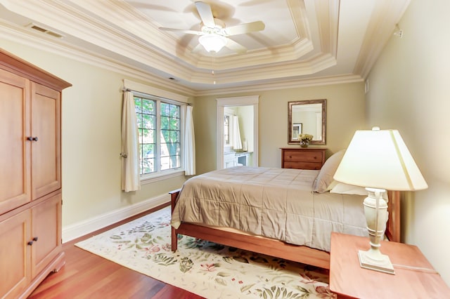 bedroom with ceiling fan, ornamental molding, a tray ceiling, and hardwood / wood-style floors