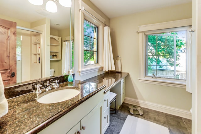 bathroom with vanity, toilet, tile patterned floors, and walk in shower