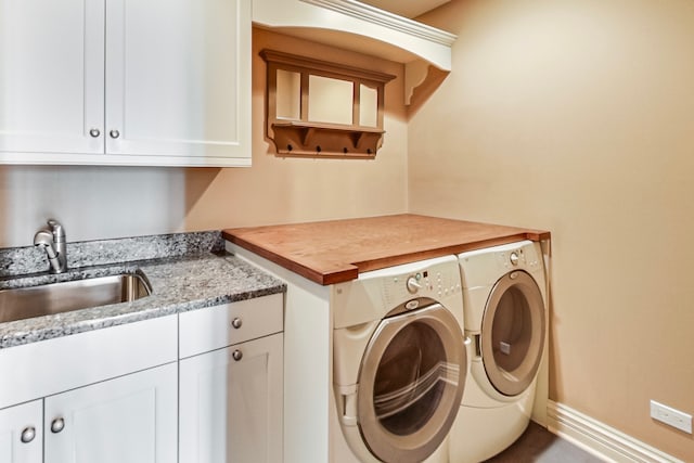 clothes washing area featuring sink, cabinets, and washer and clothes dryer