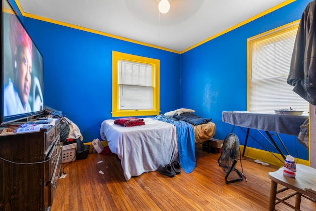 bedroom featuring ceiling fan, ornamental molding, and hardwood / wood-style floors