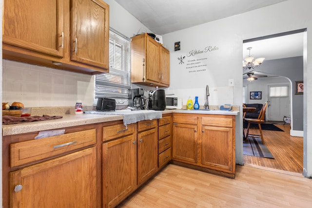 kitchen featuring sink, hanging light fixtures, ceiling fan with notable chandelier, and light hardwood / wood-style floors