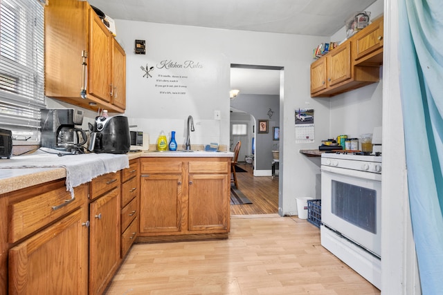 kitchen with gas range gas stove, sink, and light wood-type flooring