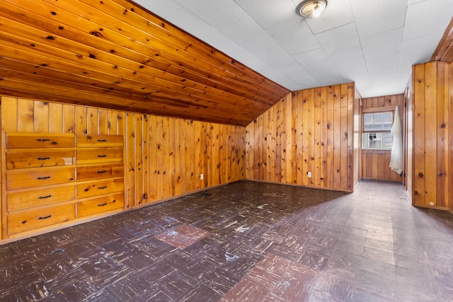 bonus room featuring lofted ceiling and wooden walls