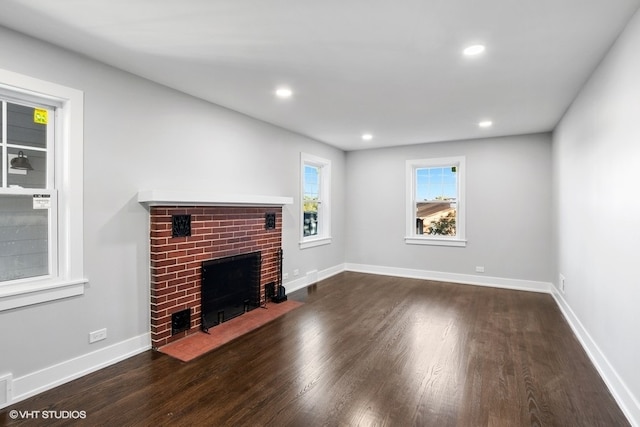 unfurnished living room with a brick fireplace and dark hardwood / wood-style floors