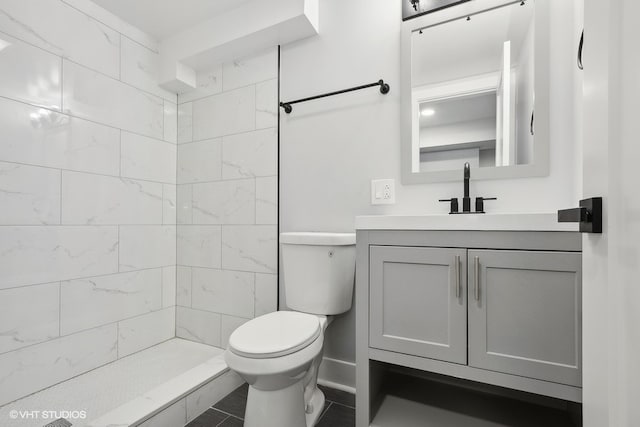 bathroom with vanity, toilet, tiled shower, and tile patterned flooring