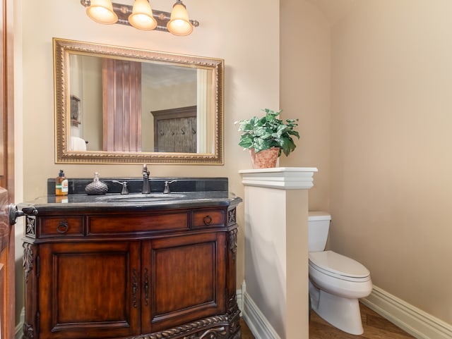 bathroom with toilet, hardwood / wood-style floors, and vanity