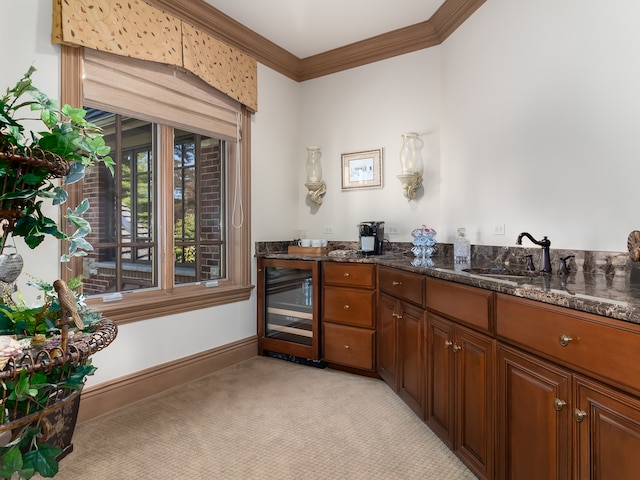 kitchen with ornamental molding, sink, dark stone counters, and beverage cooler