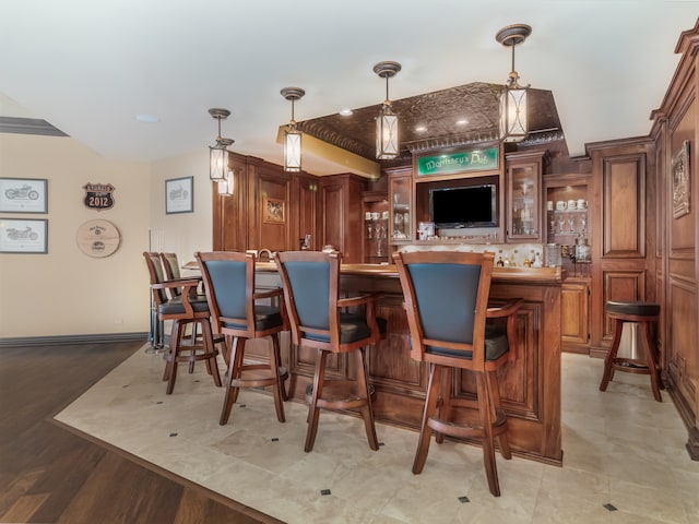 bar with light hardwood / wood-style floors and hanging light fixtures