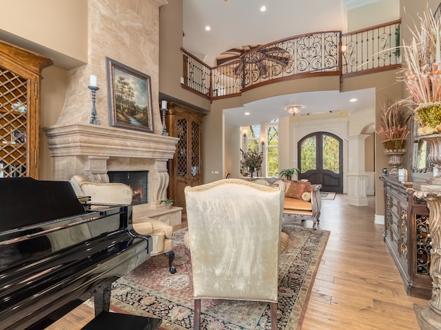 living room with a large fireplace, a towering ceiling, light hardwood / wood-style flooring, and ornamental molding