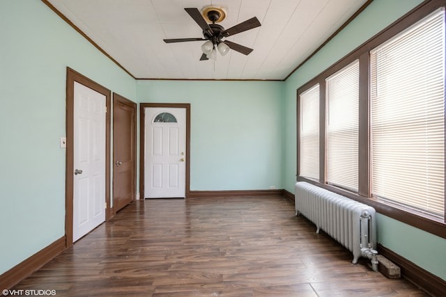 unfurnished room featuring ornamental molding, dark wood-type flooring, radiator heating unit, and ceiling fan