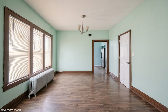 empty room featuring radiator, dark hardwood / wood-style flooring, and an inviting chandelier