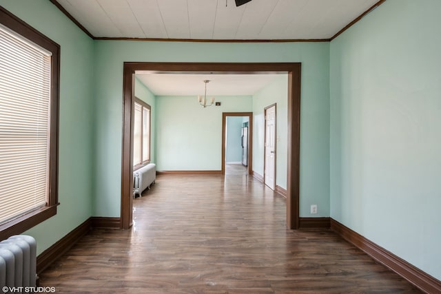 empty room with ornamental molding, dark wood-type flooring, and radiator heating unit