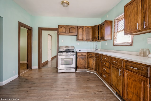 kitchen with stainless steel gas range oven and dark hardwood / wood-style flooring