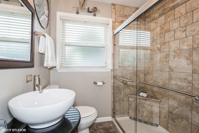 bathroom with toilet, a shower with shower door, and sink