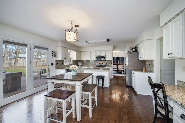 kitchen with decorative backsplash, dark hardwood / wood-style flooring, stainless steel appliances, white cabinets, and a kitchen island