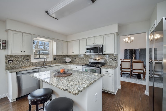 kitchen featuring stainless steel appliances, sink, white cabinets, a center island, and dark hardwood / wood-style floors