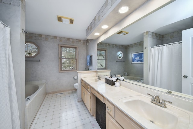 bathroom featuring vanity, toilet, and tiled tub