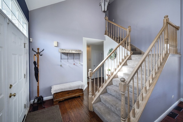 stairs with wood-type flooring and high vaulted ceiling