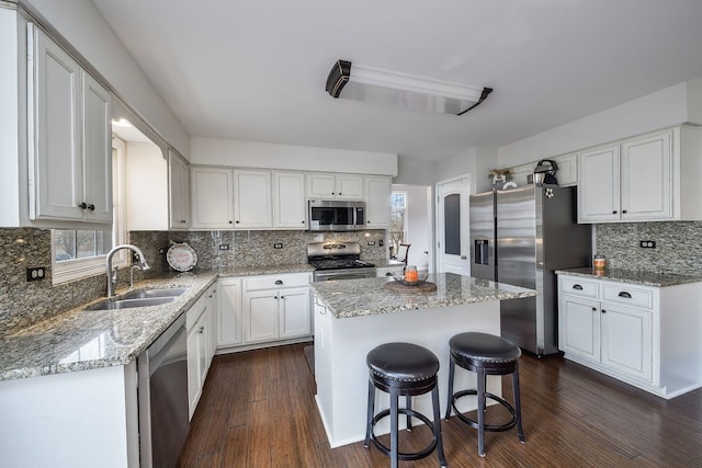 kitchen featuring white cabinets, appliances with stainless steel finishes, a center island, and sink