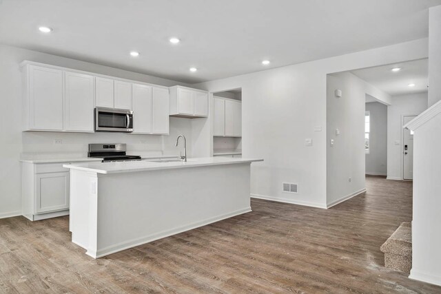 kitchen featuring white cabinetry, appliances with stainless steel finishes, light wood-type flooring, and a kitchen island with sink